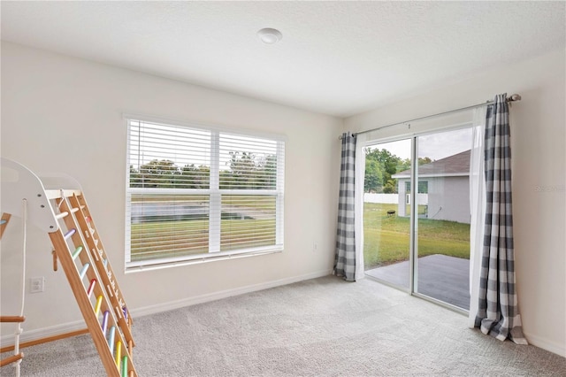 spare room featuring baseboards, a textured ceiling, and light carpet