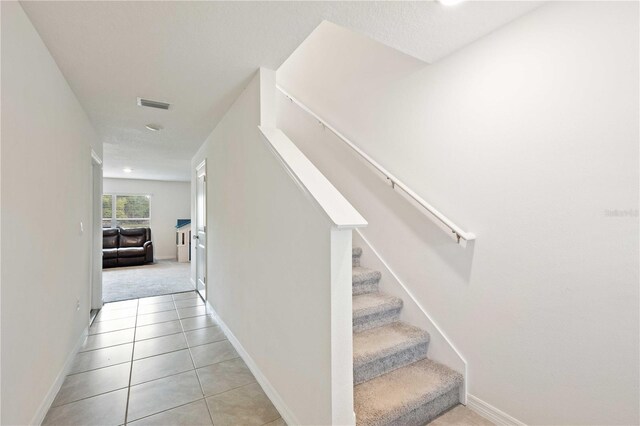 stairway featuring tile patterned flooring, baseboards, and visible vents
