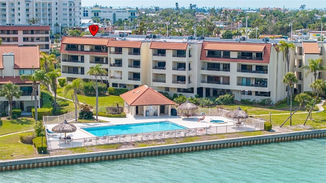 community pool with a patio area, a gazebo, a water view, and fence