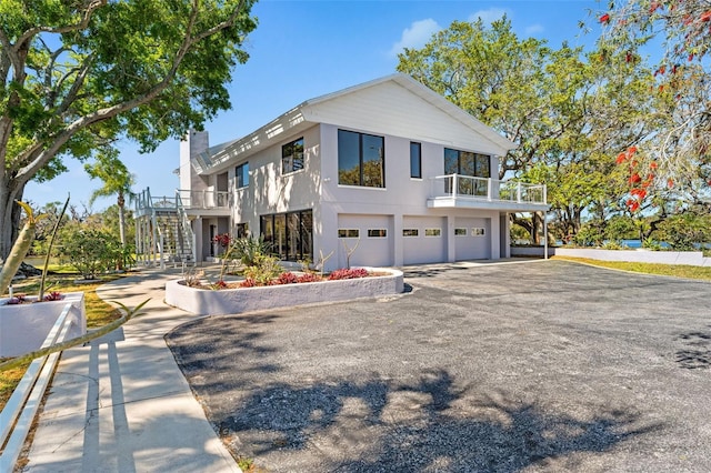 7049 Peninsular Dr, New Port Richey, FL 34652 - view of front of property featuring a garage, stairs, a balcony, driveway, and a chimney