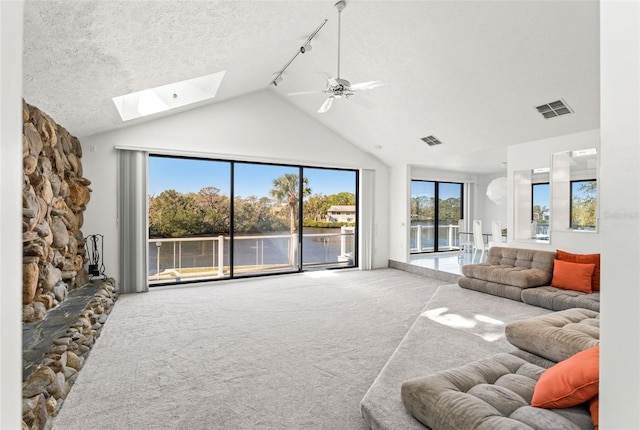 7049 Peninsular Dr, New Port Richey, FL 34652 - living room featuring carpet flooring, a skylight, a water view, track lighting, and ceiling fan
