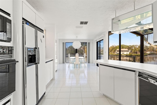 7049 Peninsular Dr, New Port Richey, FL 34652 - kitchen featuring black appliances, white cabinets, light tile patterned floors, light countertops, and modern cabinets