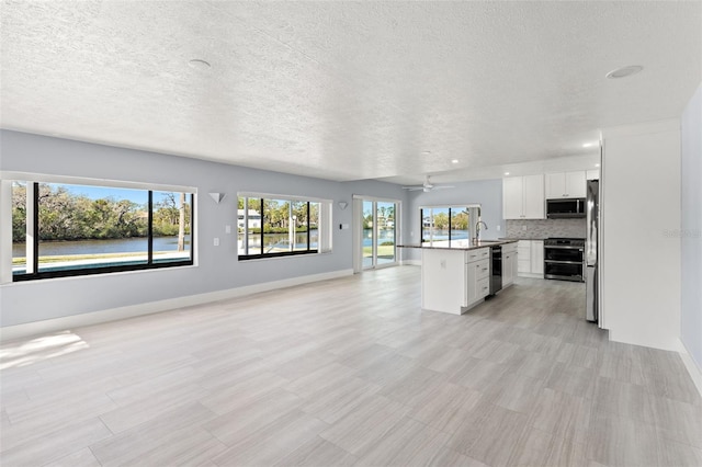 7049 Peninsular Dr, New Port Richey, FL 34652 - unfurnished living room with a sink, a textured ceiling, baseboards, and a ceiling fan