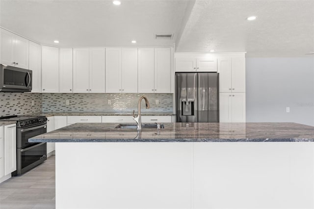 7049 Peninsular Dr, New Port Richey, FL 34652 - kitchen with stainless steel appliances, a sink, dark stone counters, backsplash, and white cabinetry