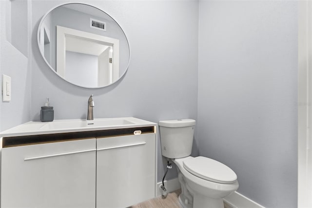 7049 Peninsular Dr, New Port Richey, FL 34652 - half bathroom featuring vanity, toilet, wood finished floors, and baseboards