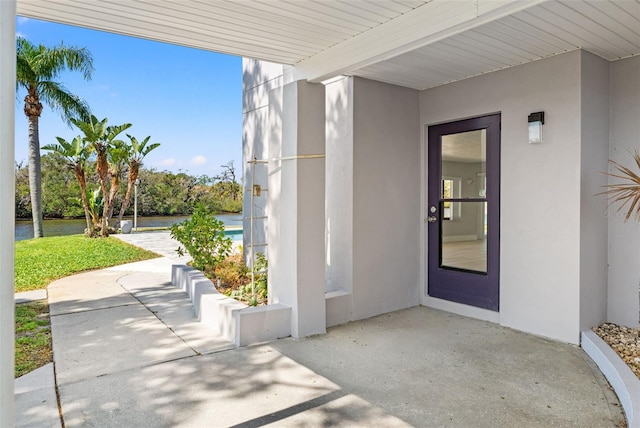 7049 Peninsular Dr, New Port Richey, FL 34652 - property entrance featuring a water view, stucco siding, and a patio area