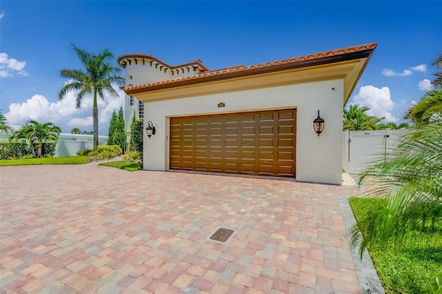 362 41st Ave, St Pete Beach, FL 33706 - garage featuring a gate, decorative driveway, and fence