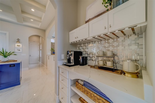 362 41st Ave, St Pete Beach, FL 33706 - kitchen with coffered ceiling, decorative backsplash, arched walkways, white cabinets, and light stone countertops