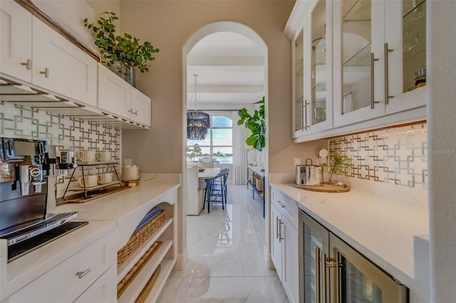 362 41st Ave, St Pete Beach, FL 33706 - kitchen with white cabinetry, marble finish floor, arched walkways, light stone counters, and glass insert cabinets