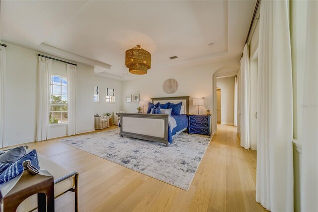 362 41st Ave, St Pete Beach, FL 33706 - bedroom with a tray ceiling, baseboards, arched walkways, visible vents, and wood finished floors