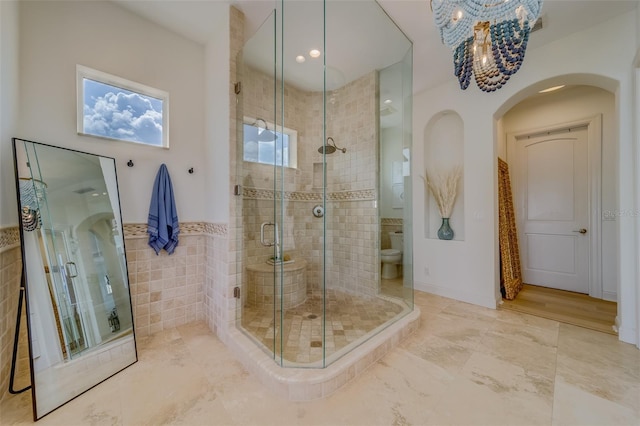 362 41st Ave, St Pete Beach, FL 33706 - bathroom with toilet, a notable chandelier, tile walls, and a shower stall