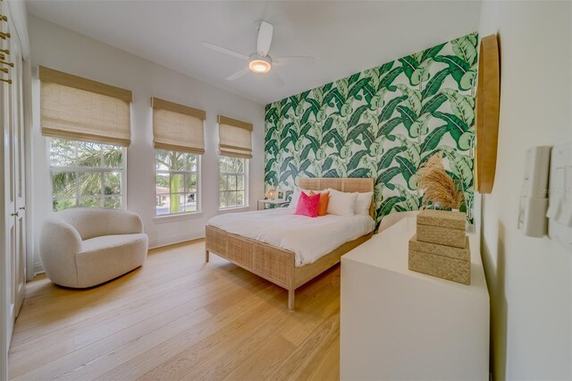 362 41st Ave, St Pete Beach, FL 33706 - bedroom with baseboards, an accent wall, wallpapered walls, ceiling fan, and light wood-style flooring