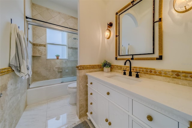 362 41st Ave, St Pete Beach, FL 33706 - bathroom featuring tile walls, marble finish floor, toilet, vanity, and shower / bath combination with glass door