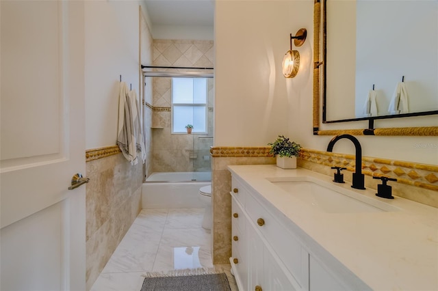 362 41st Ave, St Pete Beach, FL 33706 - full bath with tile walls, a wainscoted wall, combined bath / shower with glass door, toilet, and vanity