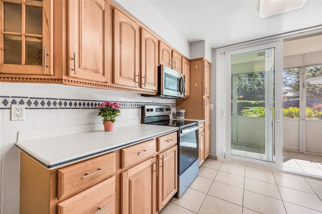 615 10th Ave NE Unit 1, Saint Petersburg, FL 33701 - kitchen with light countertops, light tile patterned floors, stainless steel appliances, decorative backsplash, and glass insert cabinets