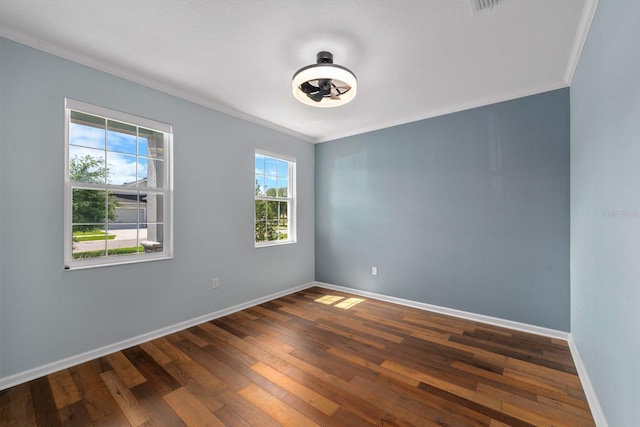 spare room featuring baseboards, dark wood finished floors, and crown molding