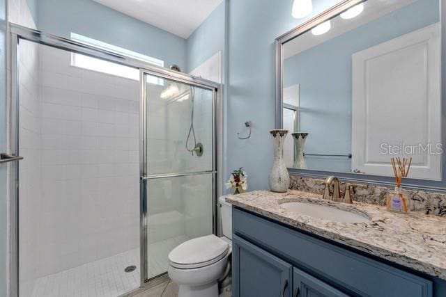 bathroom with toilet, vanity, and a stall shower