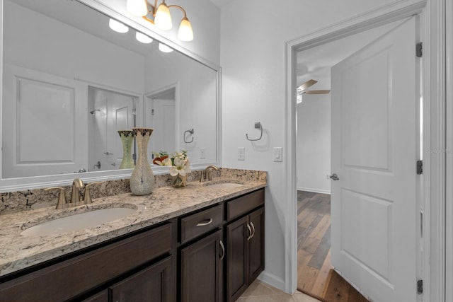 bathroom with double vanity, baseboards, ceiling fan, and a sink