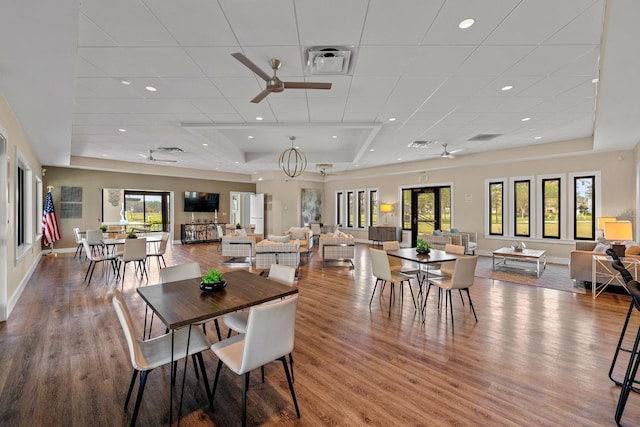 dining area featuring a raised ceiling, wood finished floors, a drop ceiling, and ceiling fan