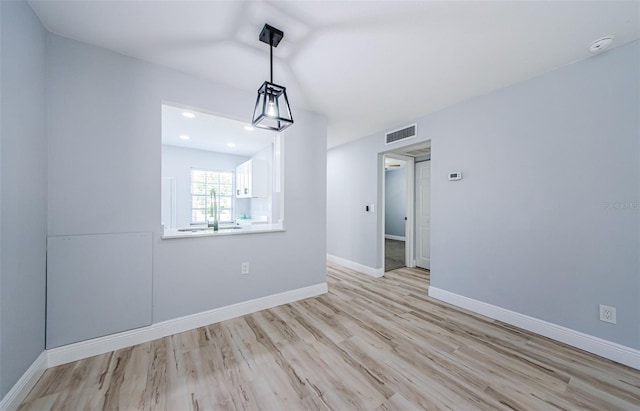 3143 Mission Grove Dr, Palm Harbor, FL 34684 - unfurnished dining area featuring light wood-type flooring, baseboards, lofted ceiling, and visible vents