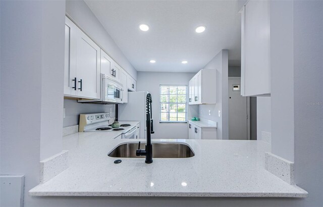 3143 Mission Grove Dr, Palm Harbor, FL 34684 - kitchen featuring white cabinets, a sink, white appliances, recessed lighting, and light stone countertops