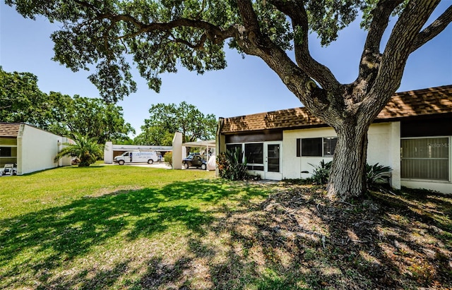 3143 Mission Grove Dr, Palm Harbor, FL 34684 - rear view of house with a yard, a shingled roof, and stucco siding
