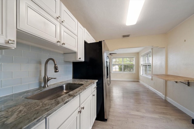 2585 9th Ave N, Saint Petersburg, FL 33713 - kitchen with a sink, light wood finished floors, decorative backsplash, stone countertops, and white cabinets