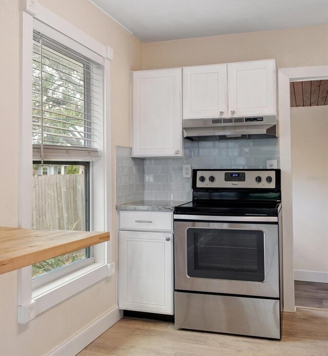 2585 9th Ave N, Saint Petersburg, FL 33713 - kitchen featuring stainless steel range with electric cooktop, under cabinet range hood, white cabinetry, backsplash, and light wood-style floors