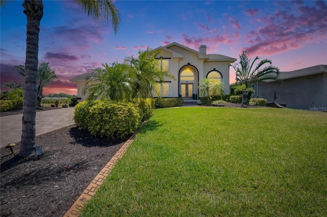 706 Bunker View Dr, Apollo Beach, FL 33572 - view of front of property with a front yard, driveway, a chimney, stucco siding, and french doors