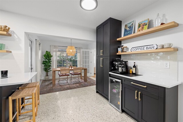 kitchen featuring light countertops, open shelves, beverage cooler, hanging light fixtures, and backsplash