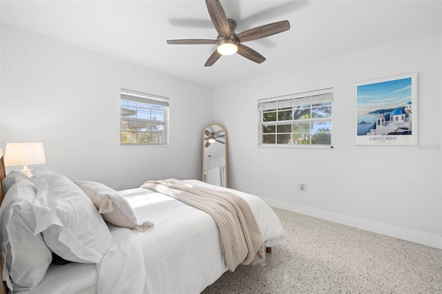 bedroom with speckled floor, baseboards, multiple windows, and ceiling fan