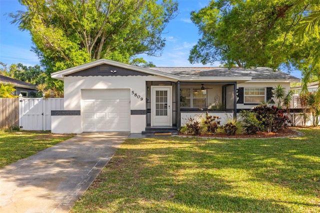 ranch-style home with driveway, an attached garage, fence, and a front yard