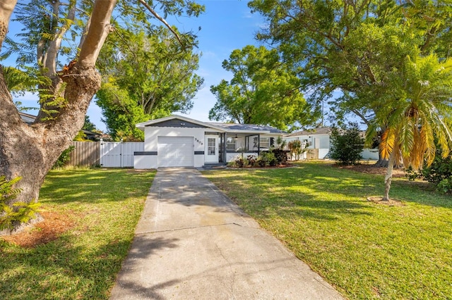 view of front of property with driveway, a garage, fence, and a front lawn