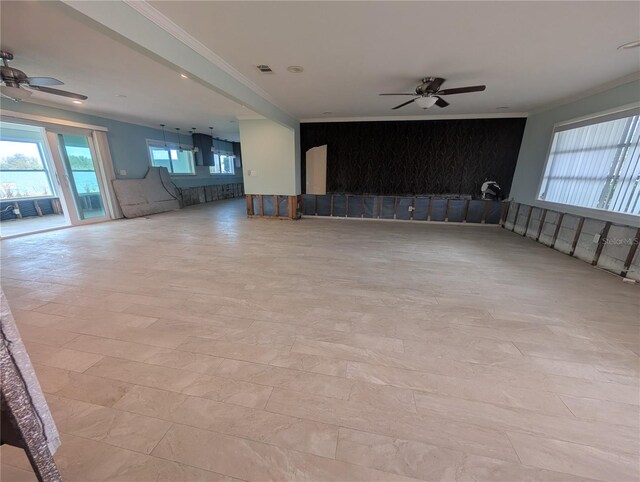 unfurnished living room featuring ornamental molding, visible vents, an accent wall, and a ceiling fan