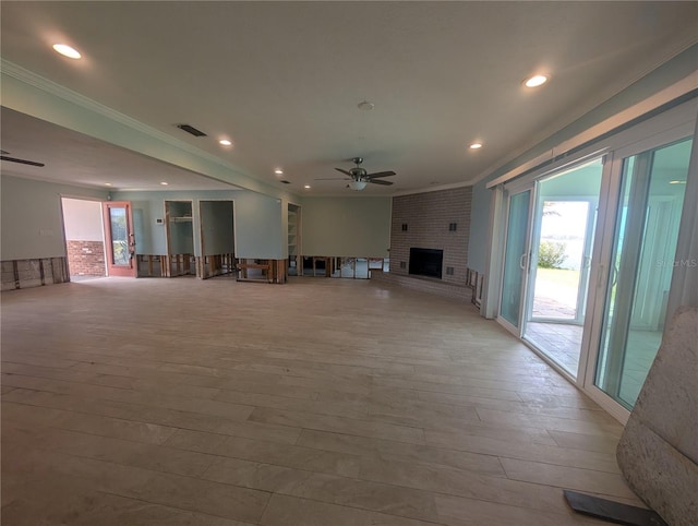 unfurnished living room with a brick fireplace, a wealth of natural light, visible vents, and a ceiling fan