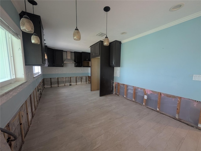 kitchen featuring wall chimney exhaust hood, dark cabinetry, light wood-type flooring, visible vents, and ornamental molding