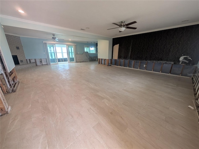 unfurnished living room with a ceiling fan, ornamental molding, an accent wall, and light wood-type flooring