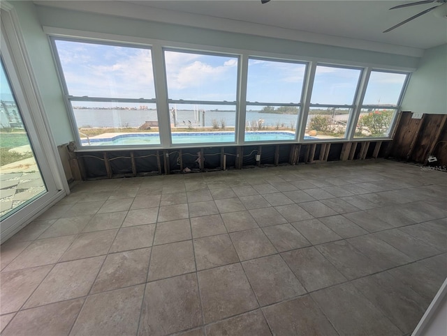 unfurnished sunroom featuring a wealth of natural light, a water view, and ceiling fan