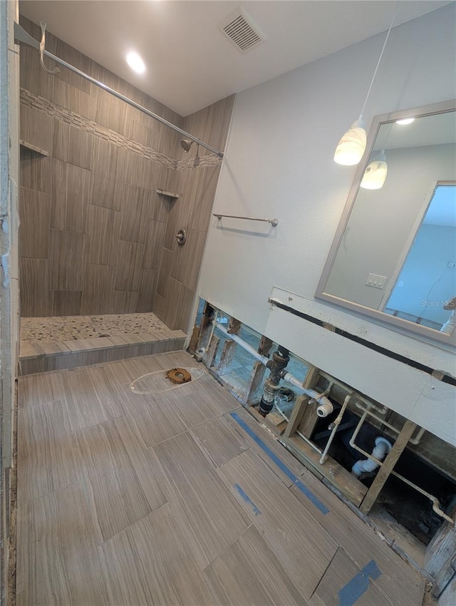 bathroom with a tile shower and visible vents