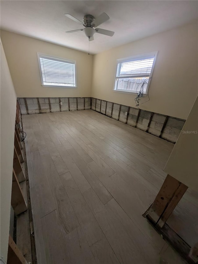 spare room with a wealth of natural light, wood finished floors, and ceiling fan