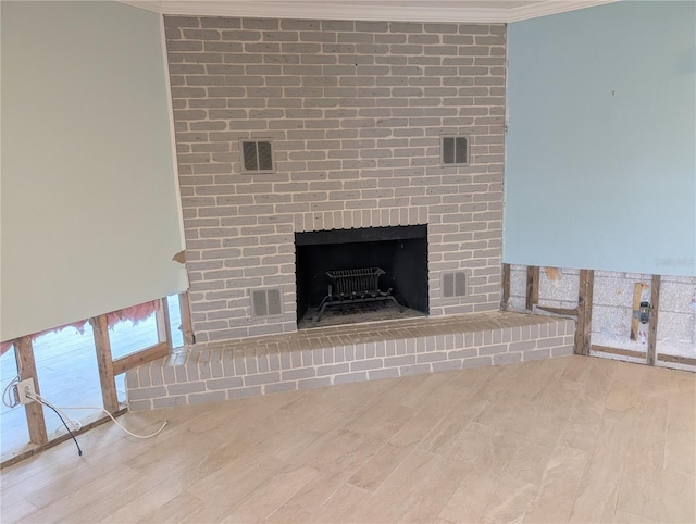 room details with a brick fireplace, visible vents, ornamental molding, and wood finished floors