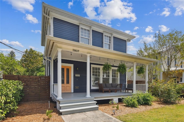 view of front of home featuring outdoor lounge area, a porch, and fence