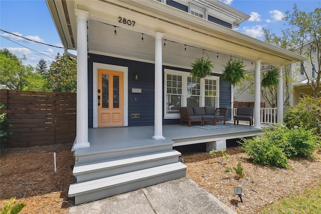 property entrance featuring an outdoor hangout area, covered porch, and fence