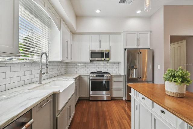 kitchen with dark wood-style flooring, stainless steel appliances, decorative backsplash, butcher block counters, and white cabinets