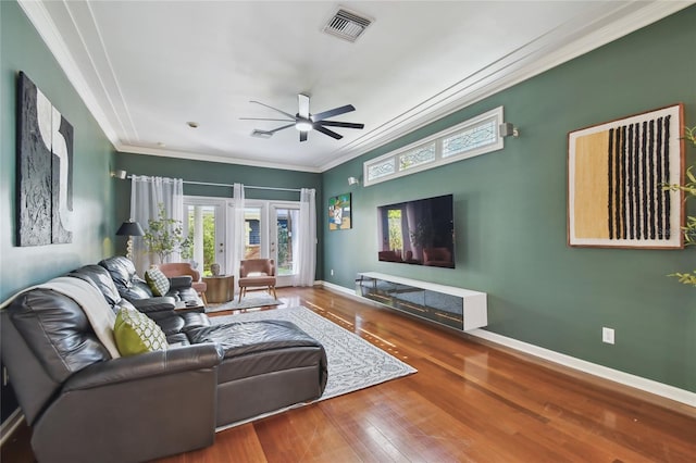 living room featuring a ceiling fan, wood-type flooring, baseboards, visible vents, and ornamental molding