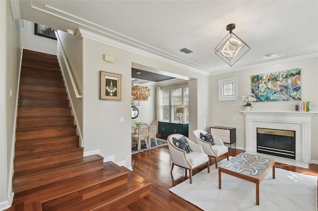 living area with stairs, visible vents, crown molding, and wood finished floors
