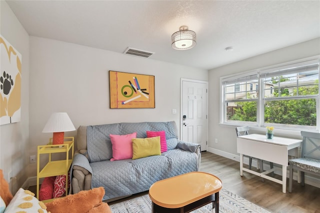 living area with baseboards, visible vents, and wood finished floors