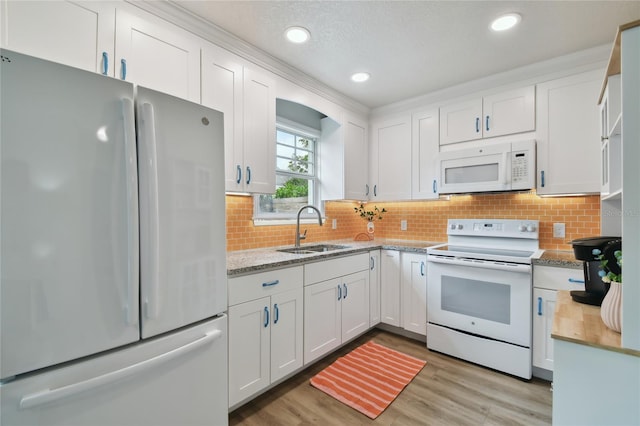 kitchen with white appliances, white cabinetry, light wood-type flooring, and a sink