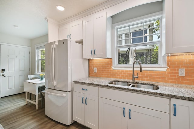 kitchen with backsplash, a sink, freestanding refrigerator, wood finished floors, and white cabinets