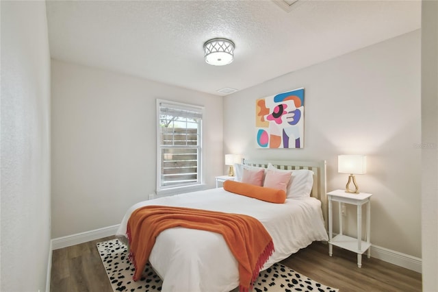 bedroom featuring a textured ceiling, baseboards, and wood finished floors